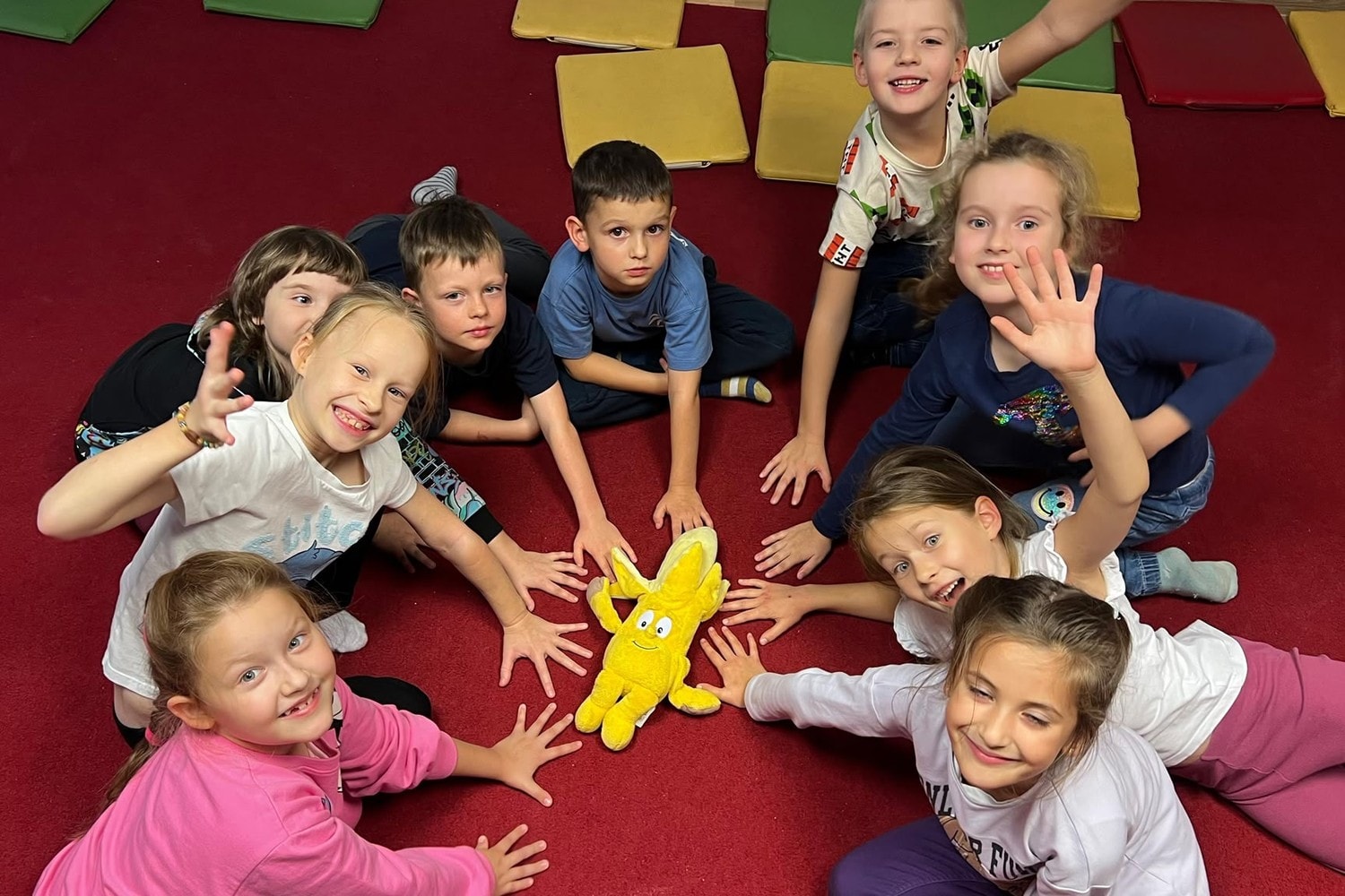 Dzieci w kręgu na dywanie z maskotką podczas zajęć Genki English