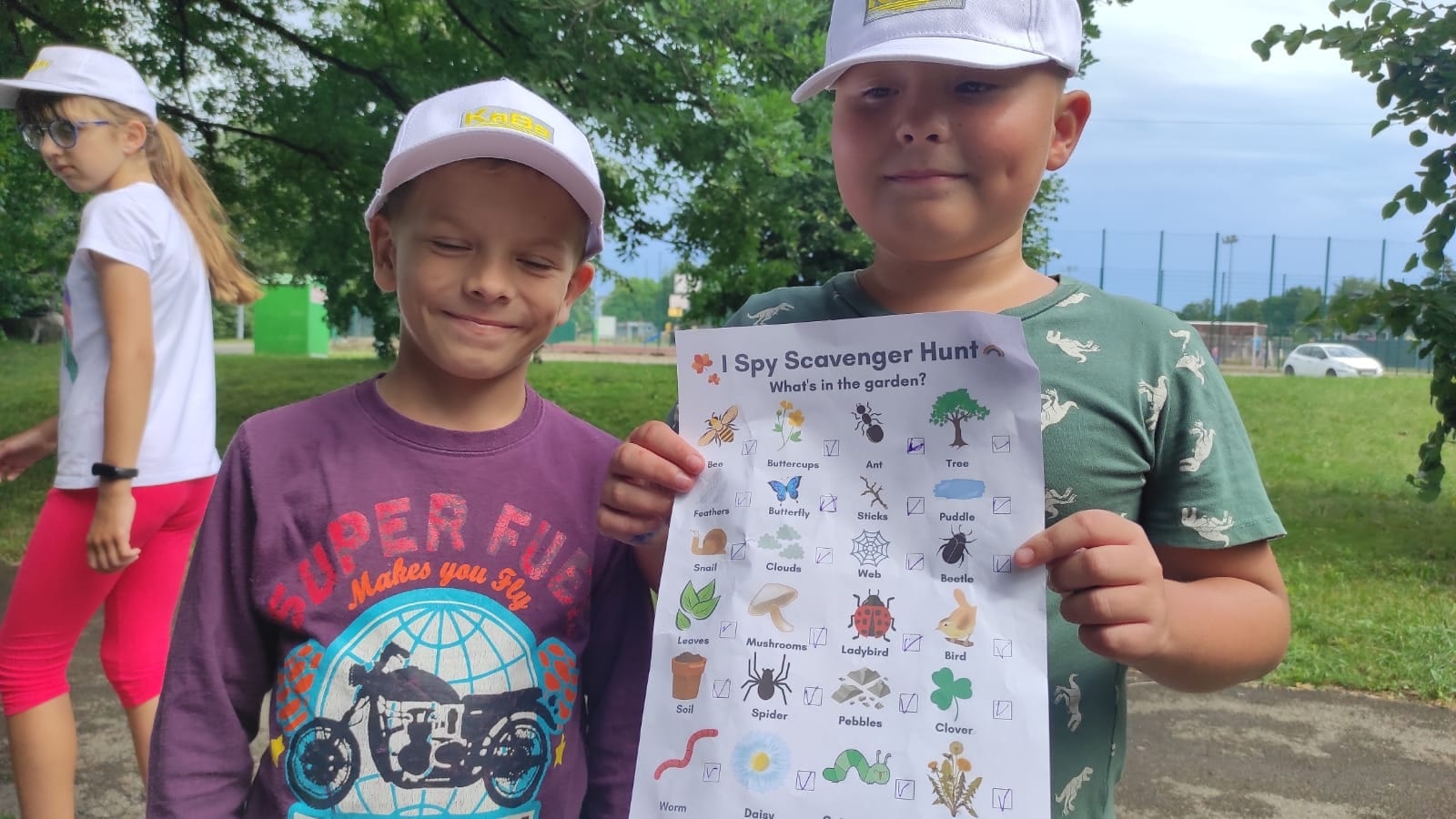 Dzieci z kartami pracy po angielsku podczas zajęć w plenerze