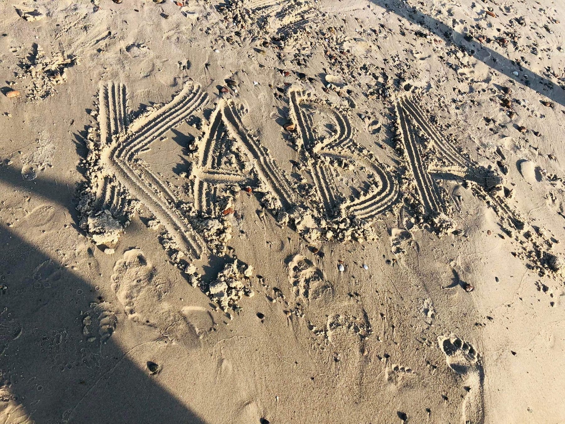 Napis KaBa narysowany na piasku na plaży